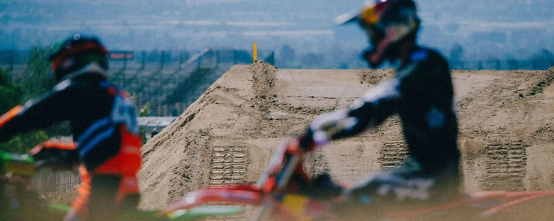 Motocross riders racing past a dirt jump